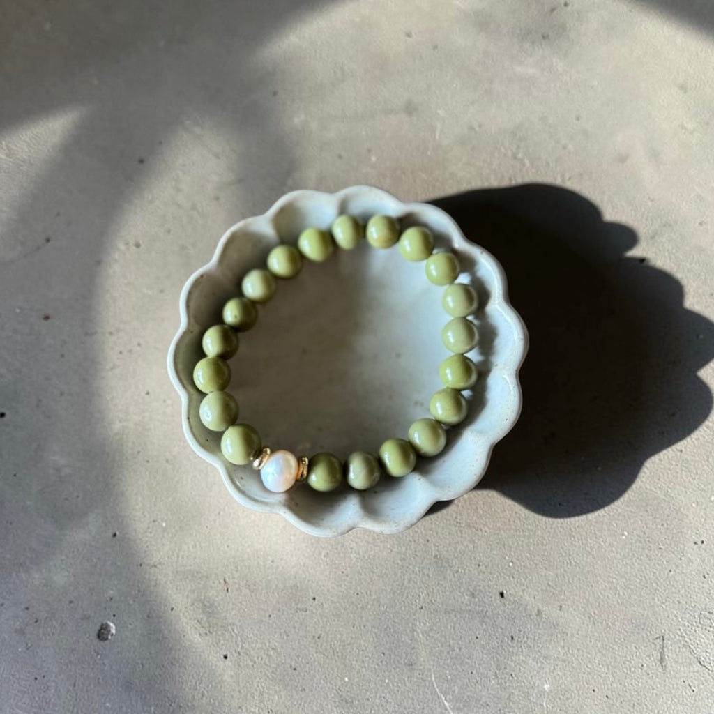 8mm Alaskan Avocado  (a green color) with fresh water pearl and gold spacers in a bracelet form. 