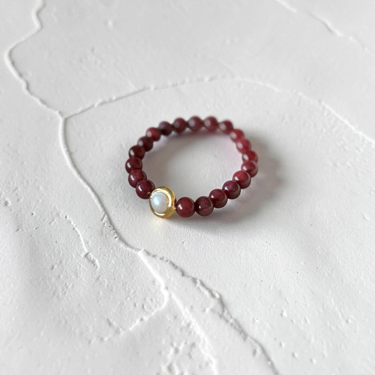 8mm Red Garnet Jade Bead Bracelet with a Gold And Pearl Accent. Accent has a round pearl with gold surrounding the pearl itself. 