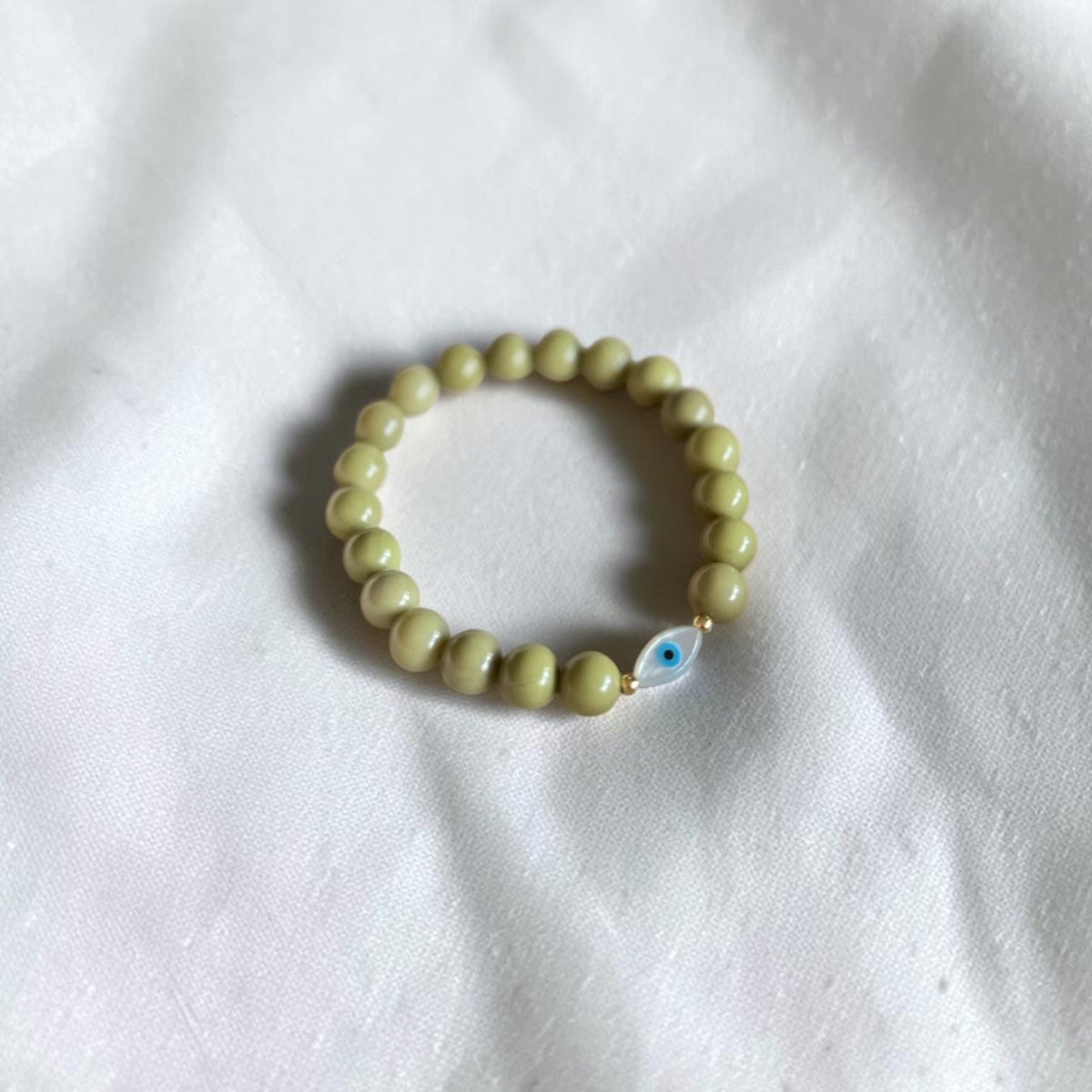 Close-up of The Romy Bracelet showing the mother of pearl evil eye charm and gold filled beads — Poppies & Jules