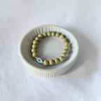 Close-up of The Romy Bracelet showing the mother of pearl evil eye charm and gold filled beads — Poppies & Jules
