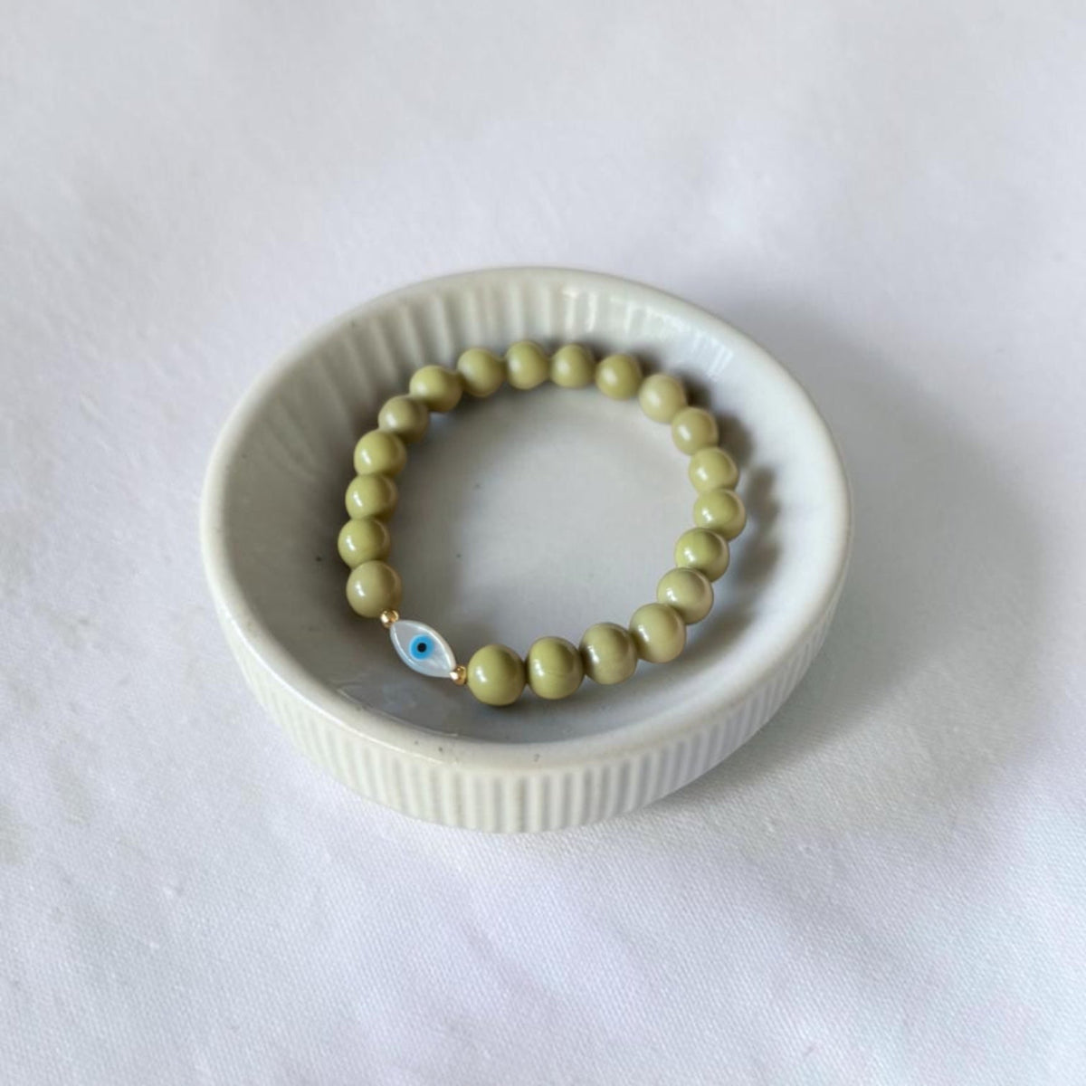 Close-up of The Romy Bracelet showing the mother of pearl evil eye charm and gold filled beads — Poppies & Jules