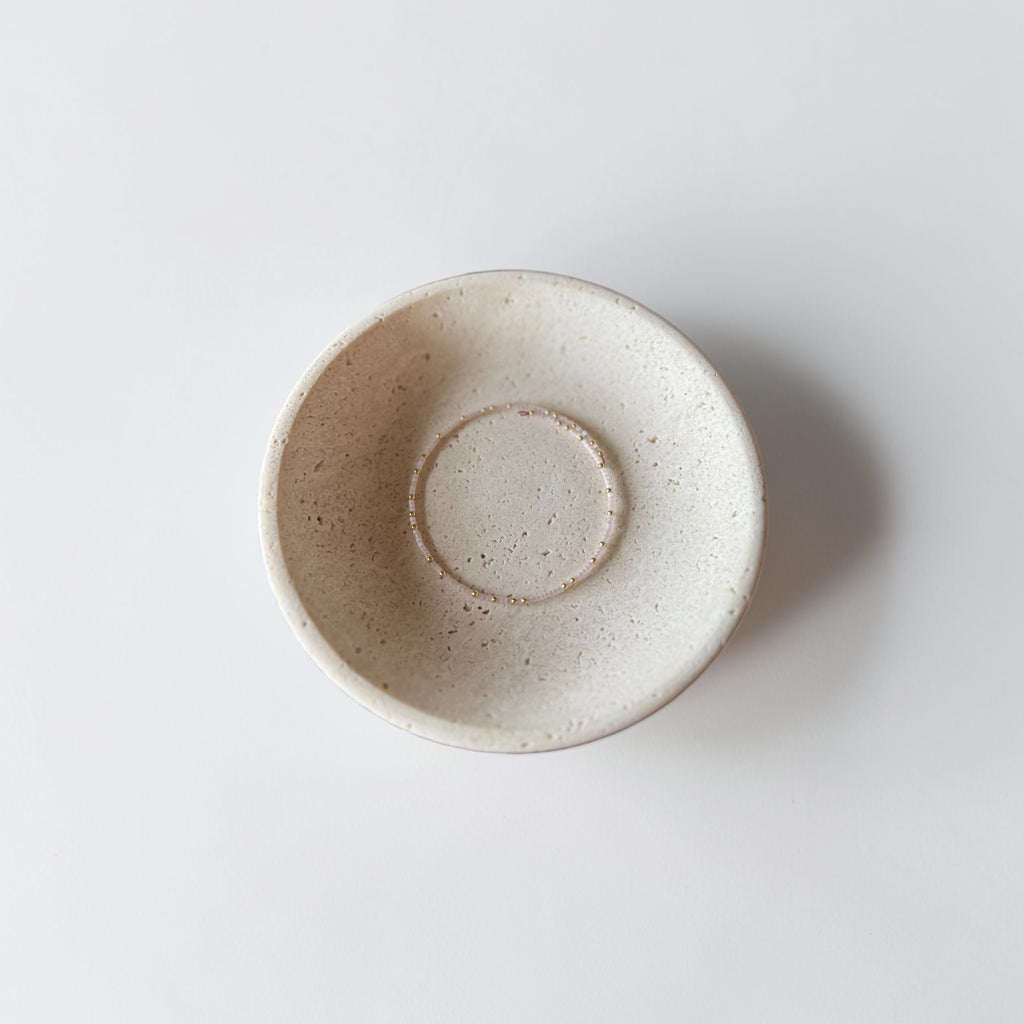 A handmade ceramic bowl with a speckled, matte off-white finish, photographed from directly above on a clean white background.