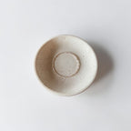 A handmade ceramic bowl with a speckled, matte off-white finish, photographed from directly above on a clean white background.