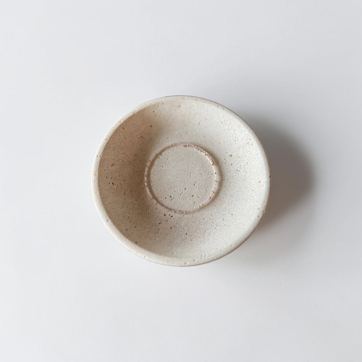 A handmade ceramic bowl with a speckled, matte off-white finish, photographed from directly above on a clean white background.