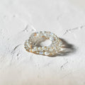 A stack of three beaded rings featuring white pearls, clear faceted beads, and small iridescent shell accents, displayed on a textured light beige surface.