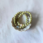 Close-up of The Romy Bracelet showing the mother of pearl evil eye charm and gold filled beads — Poppies & Jules> it also has another green bracelet wth a pearl. 