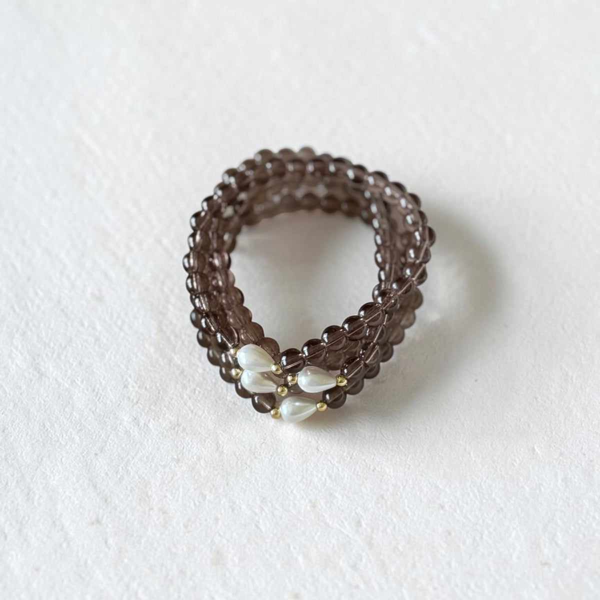 smoky brown bracelets in a stack. With a teardrop pearl and gold filled bead placed on both sides of the pearl.