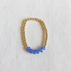 This is a close up of a gold filled bracelet with blue rondelle beads in a cluster in front. 