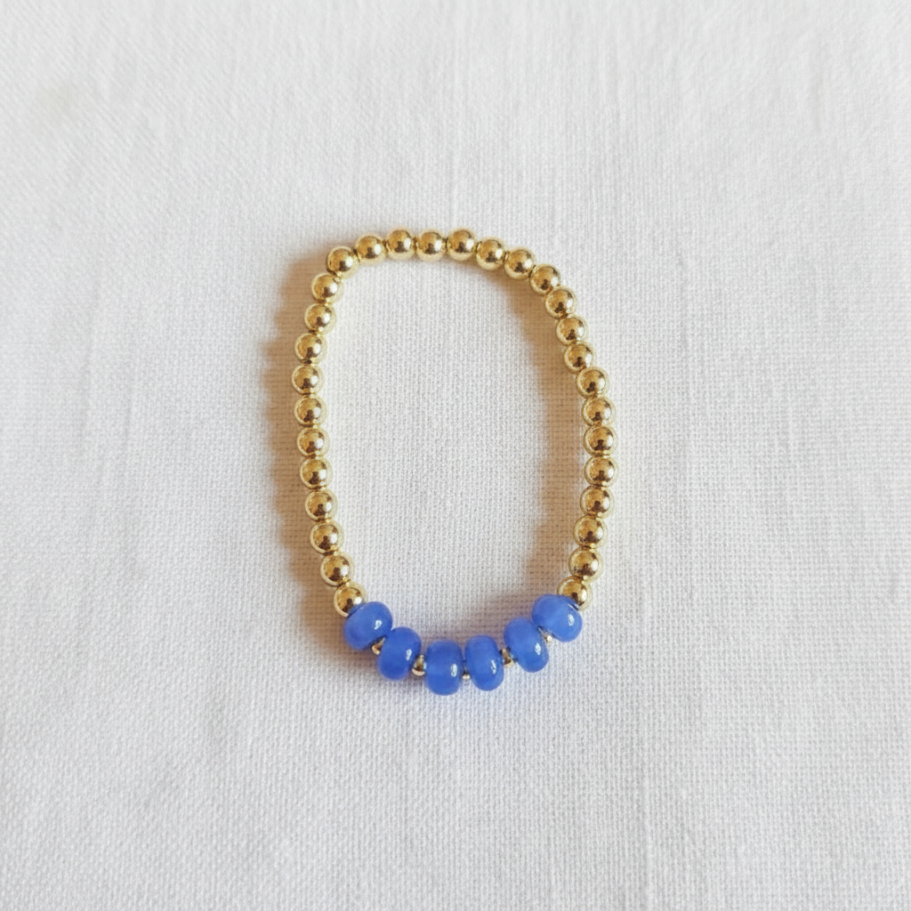 This is a close up of a gold filled bracelet with blue rondelle beads in a cluster in front. 