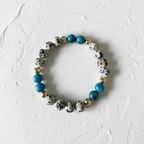 The Dottie Bracelet - White Background with texture with a bead bracelet zoomed in.