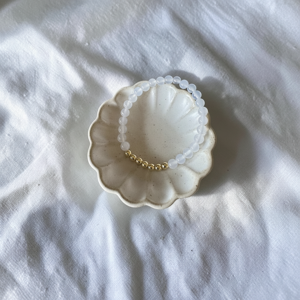 The Faith Bracelet is whiteish see through bead witha cluster of gold filled beads sititn on a dish. 