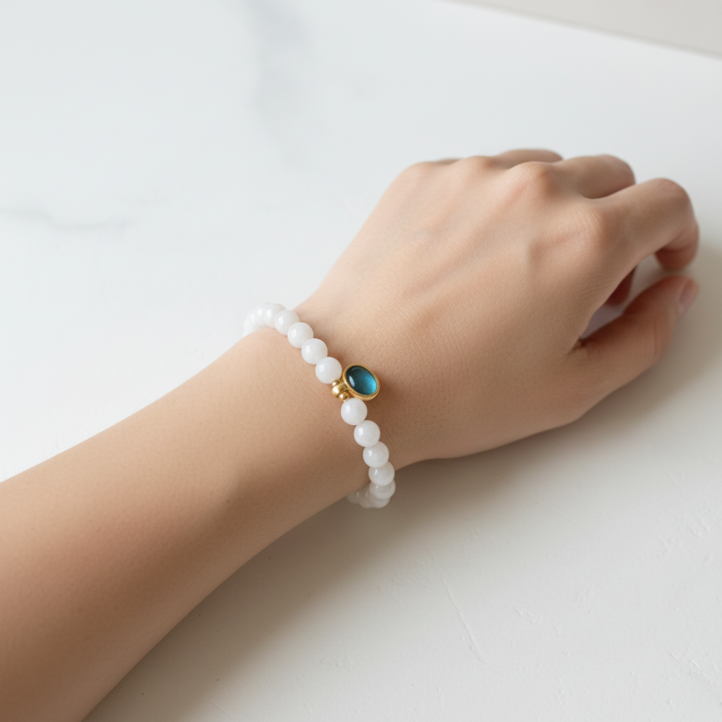 The Harper Bracelet — wrist shot, oval charm. charm is sitting next to white beads.