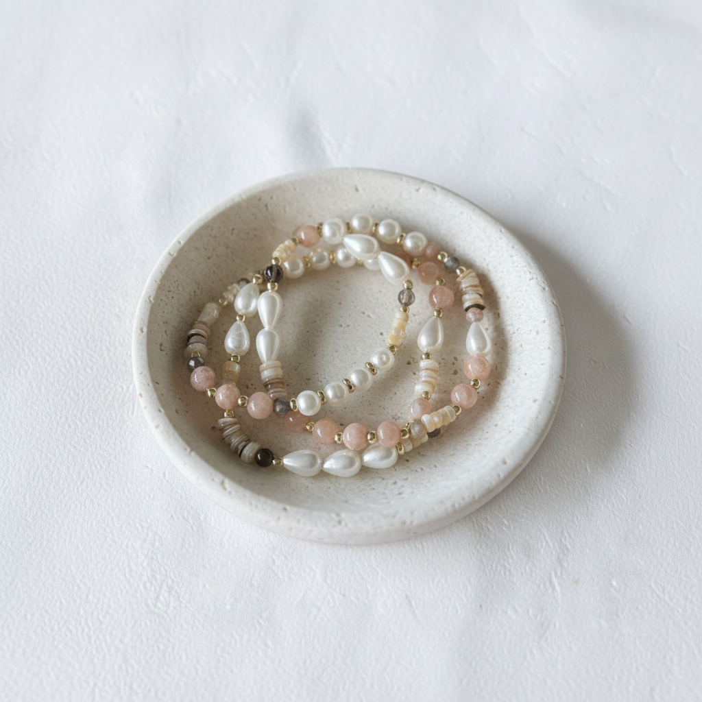 The Jules Bracelet flat lay in a ceramic dish. there are 3 bracelets with differnet looks of beads, spacers and accents.