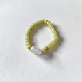 The Junelle Bracelet is sitting on white background. Close up of rondelle green beads with a long rectangle pearl. Gold plated spacers surrounding the pearl.