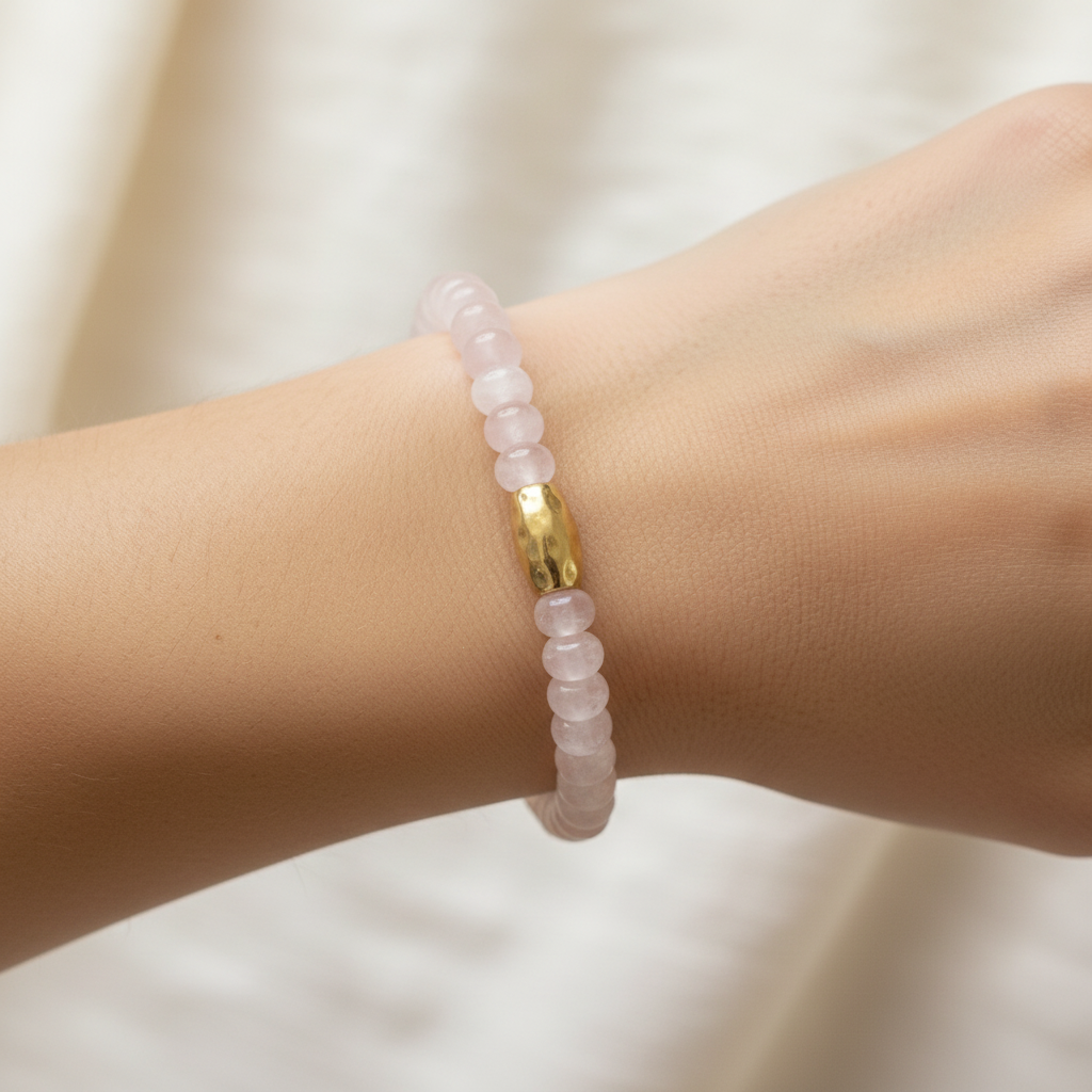 The Lila Bracelet on wrist. This is a close up of an arm. The light pink rondlle beads and gold barrel accent is front in center.