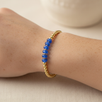 The Murphy Bracelet on wrist. This is a close up of the arm with gold filled beads. In the center are blue rondelle beads in a cluster. 