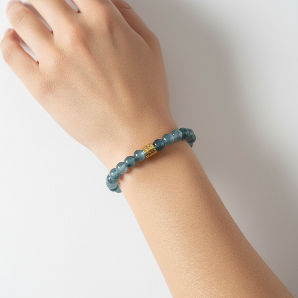 The Sailor Bracelet - wrist shot. This is a close up of a female wrist. The beads are a translucent like tie dye blue beads with a gold rectangle barrel in the center.