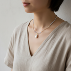 The Veda Necklace - on neck. Close up a female wearing a necklace. Necklace is seed beads with a fresh water pearl charm that hangs in the middle.